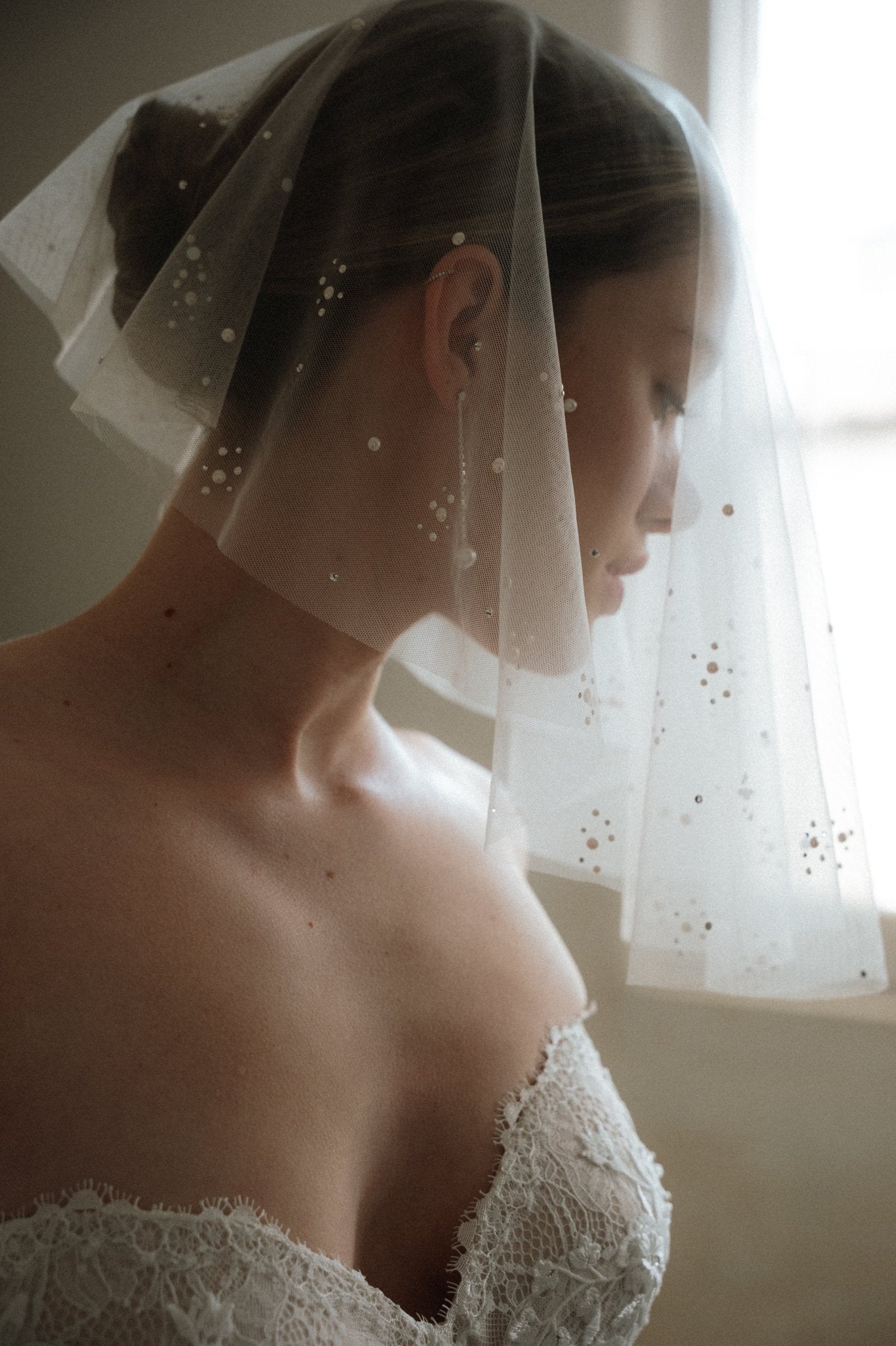 Bride wears a sheer tulle drop micro veil with pearl and crystal embellishments 