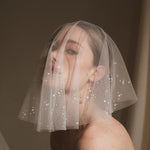 Bride wears a sheer tulle drop micro veil with pearl and crystal embellishments 
