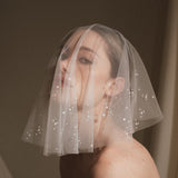 Bride wears a sheer tulle drop micro veil with pearl and crystal embellishments 