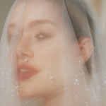 Bride wears a sheer tulle drop micro veil with pearl and crystal embellishments 