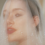 Bride wears a sheer tulle drop micro veil with pearl and crystal embellishments 
