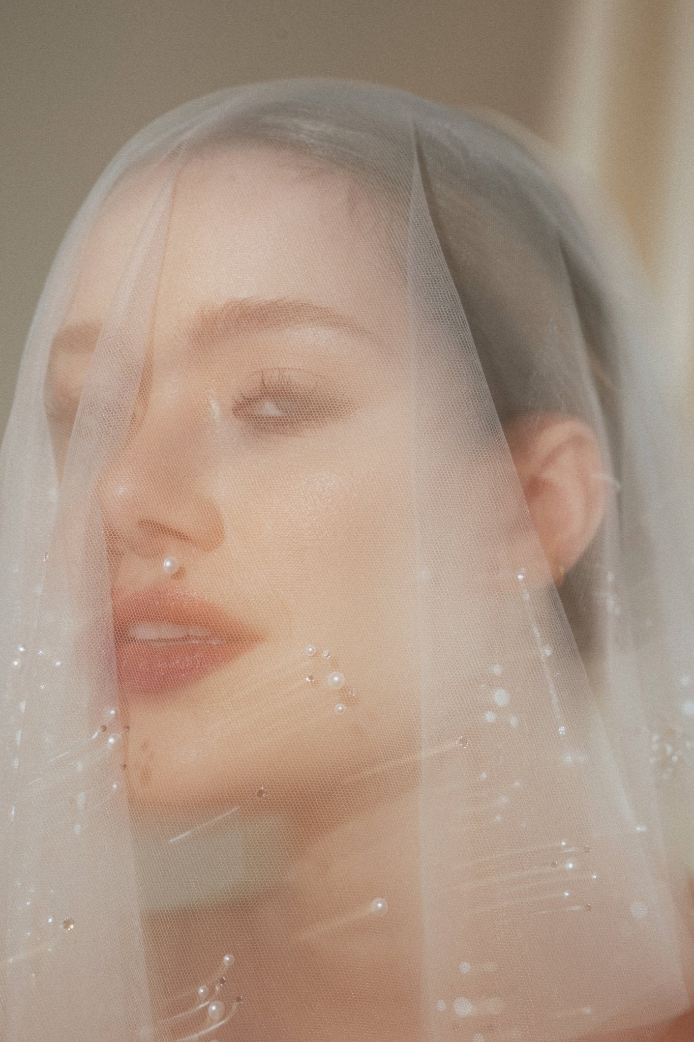 Bride wears a sheer tulle drop micro veil with pearl and crystal embellishments 