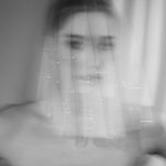 Bride wears a sheer tulle drop micro veil with pearl and crystal embellishments 