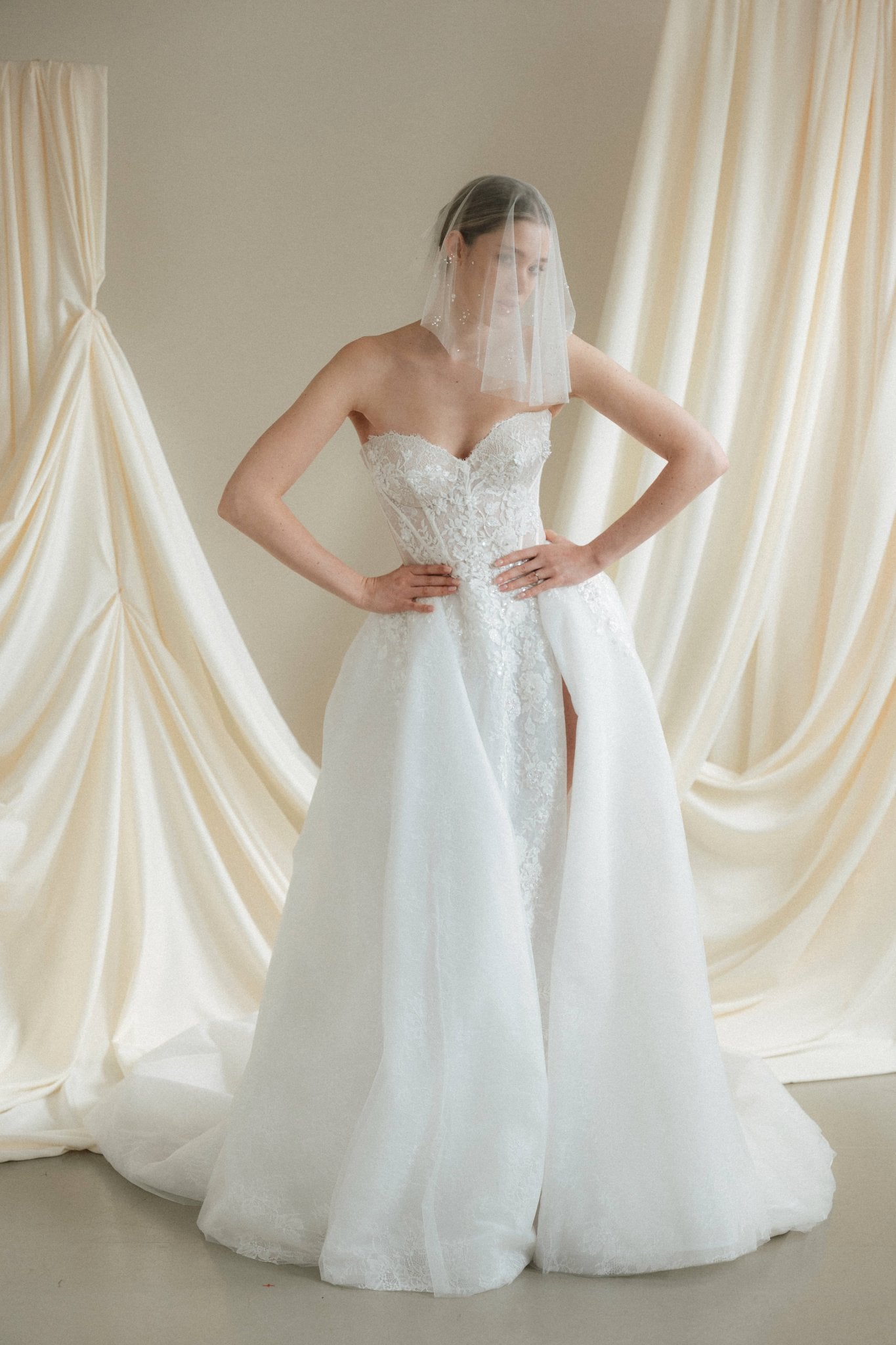 Bride wears a sheer tulle drop micro veil with pearl and crystal embellishments 