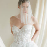 Bride wears a sheer tulle drop micro veil with pearl and crystal embellishments 