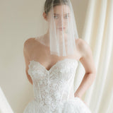 Bride wears a sheer tulle drop micro veil with pearl and crystal embellishments 
