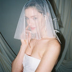 Bride wears a sheer tulle drop micro veil with pearl and crystal embellishments 
