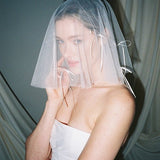 Bride wears a sheer tulle drop micro veil with pearl and crystal embellishments 