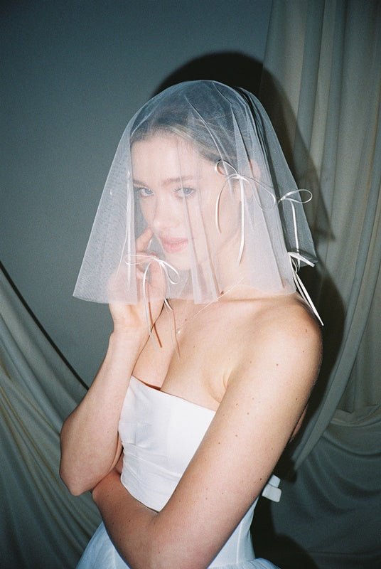 Bride wears a sheer tulle drop micro veil with pearl and crystal embellishments 