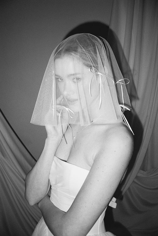 Bride wears a sheer tulle drop micro veil with pearl and crystal embellishments 