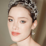Woman wearing a statement sparkling silver crystal crown with matching crystal drop earrings