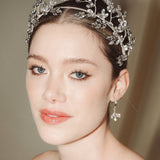 Woman wearing a statement sparkling silver crystal crown with matching crystal drop earrings