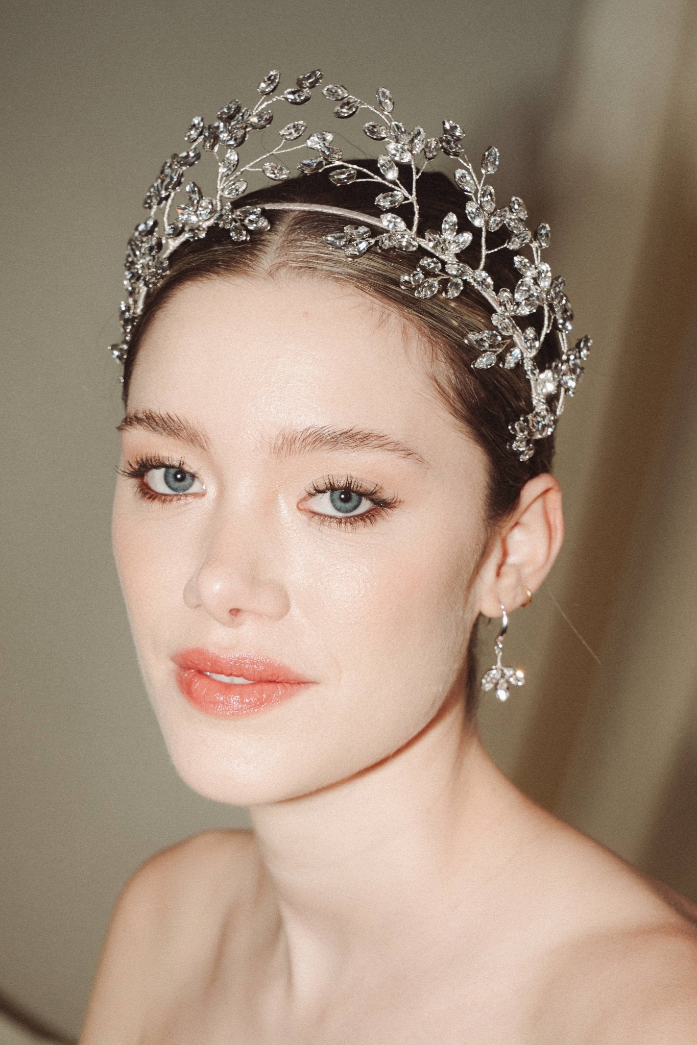 Woman wearing a statement sparkling silver crystal crown with matching crystal drop earrings