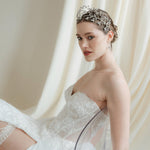 bride in a white wedding dress reclines in a crown against an ivory draped background