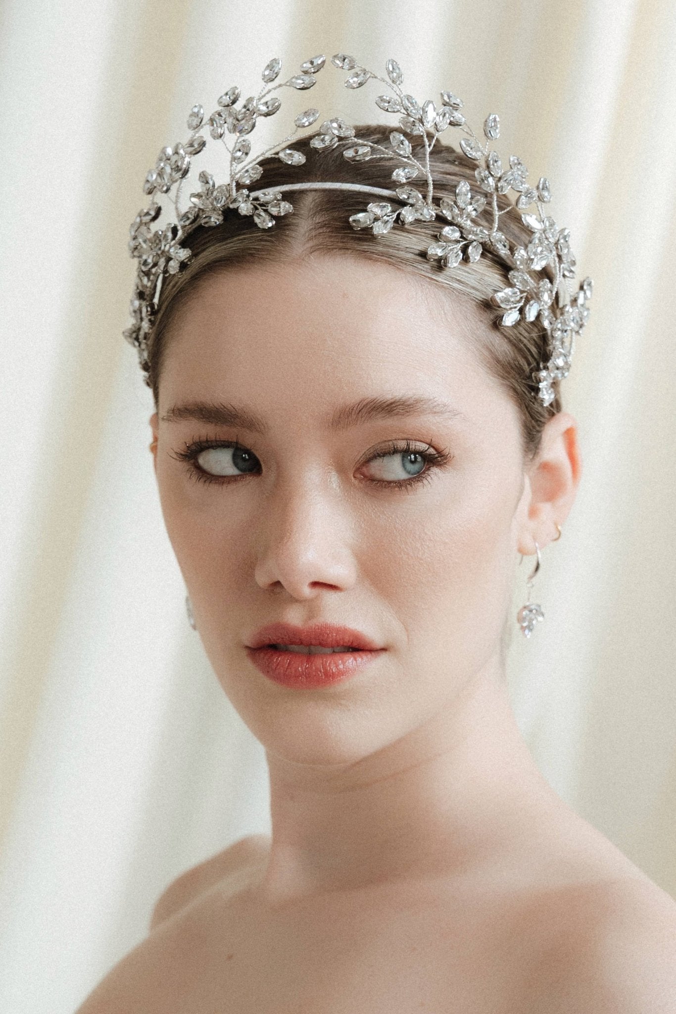 Woman wearing a wedding dress and tiara against a white curtain