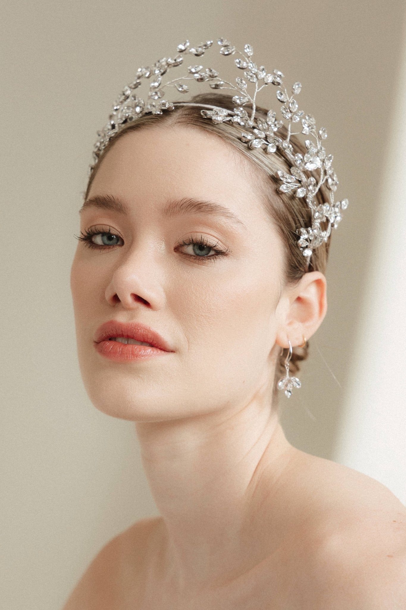 Woman wearing a silver tiara against a neutral background