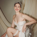 bride wears sparkling crystal tiara, smiling broadly while showing her garter through a slit in her ballgown