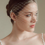 Bride wears a short merry widow mask birdcage veil with Perla pearl cluster hair pins and Dina Short gold round pearl stud drop earrings