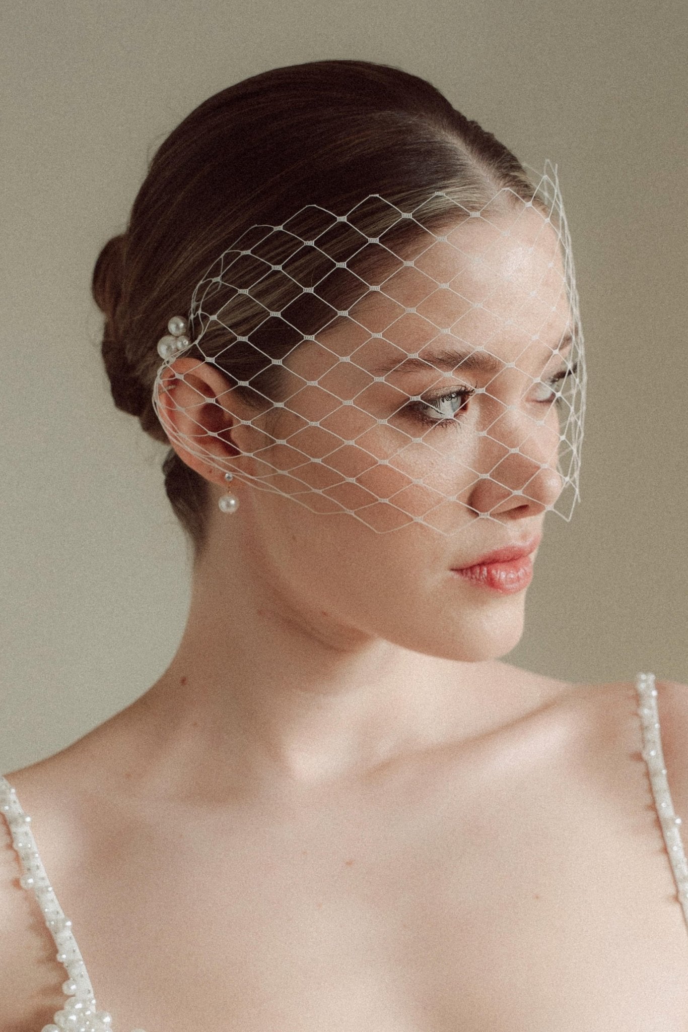 Bride wears a short merry widow mask birdcage veil with Perla pearl cluster hair pins and Dina Short gold round pearl stud drop earrings