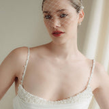 Bride wears a short merry widow mask birdcage veil with Perla pearl cluster hair pins and Dina Short gold round pearl stud drop earrings