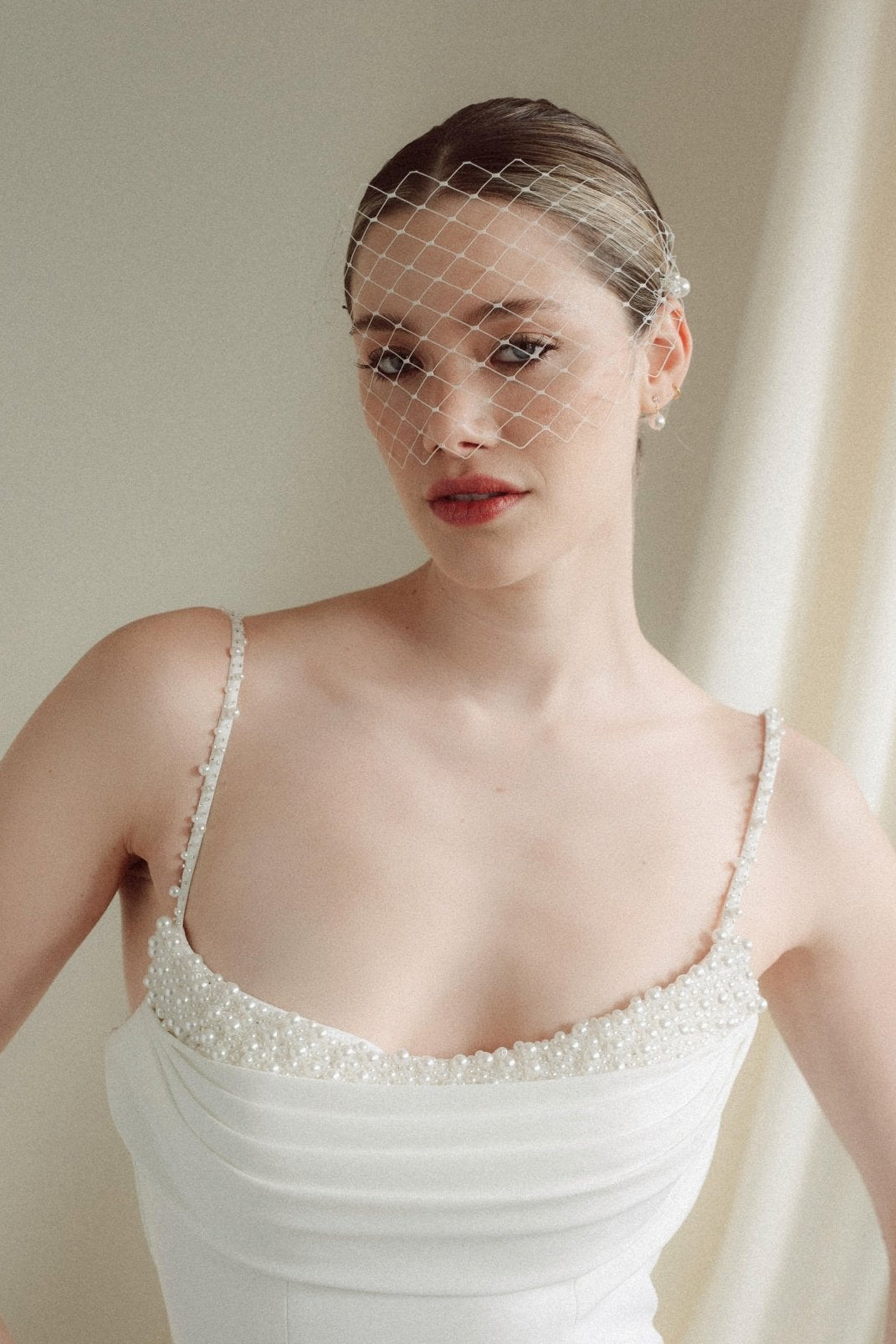 Bride wears a short merry widow mask birdcage veil with Perla pearl cluster hair pins and Dina Short gold round pearl stud drop earrings