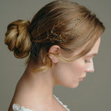 Wedding hair vine - model wears a gold leafy delicate hair vine above her ear with a low bun 