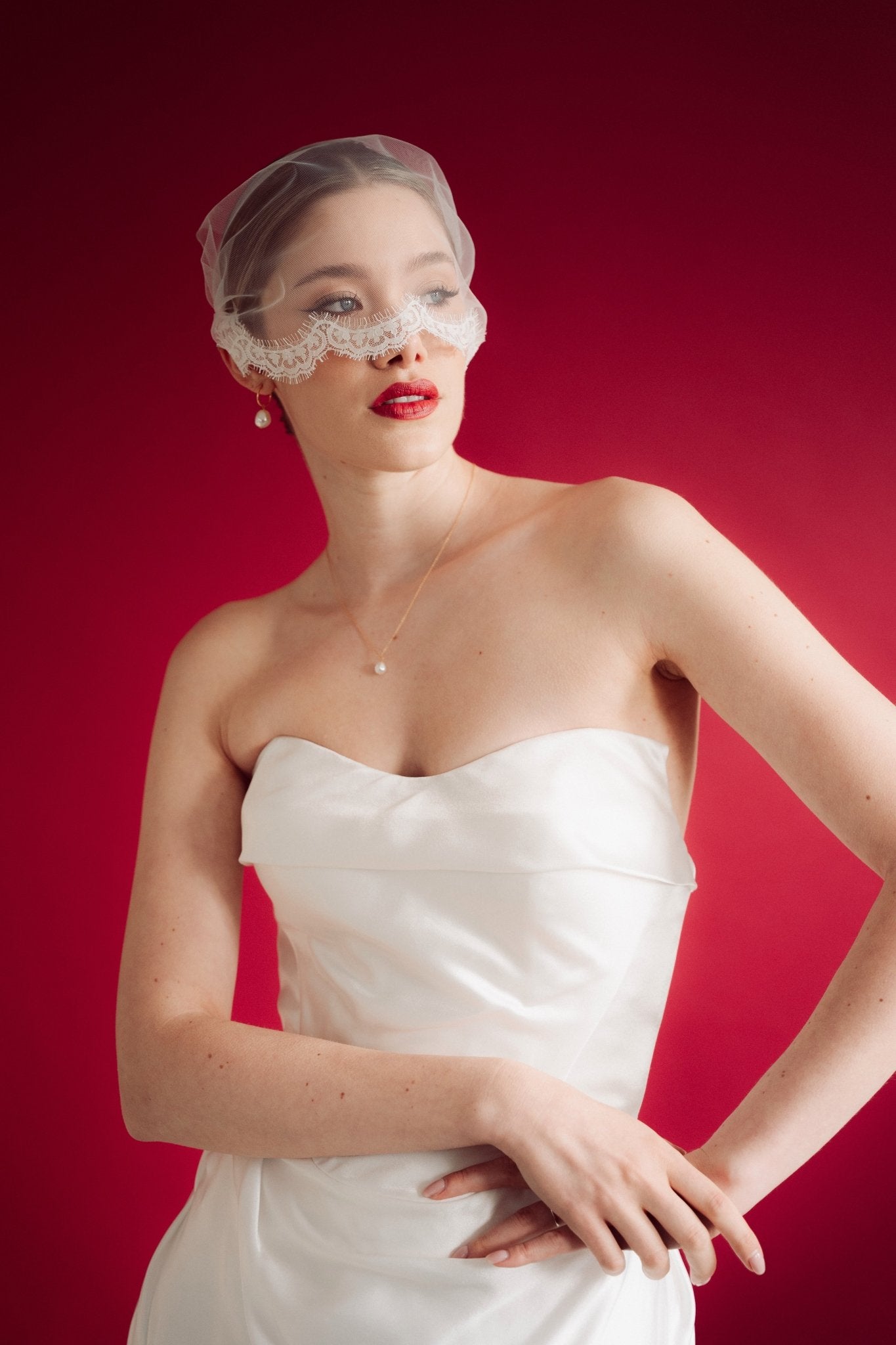 bride wearing a sheer micro veil with lace details against a red background