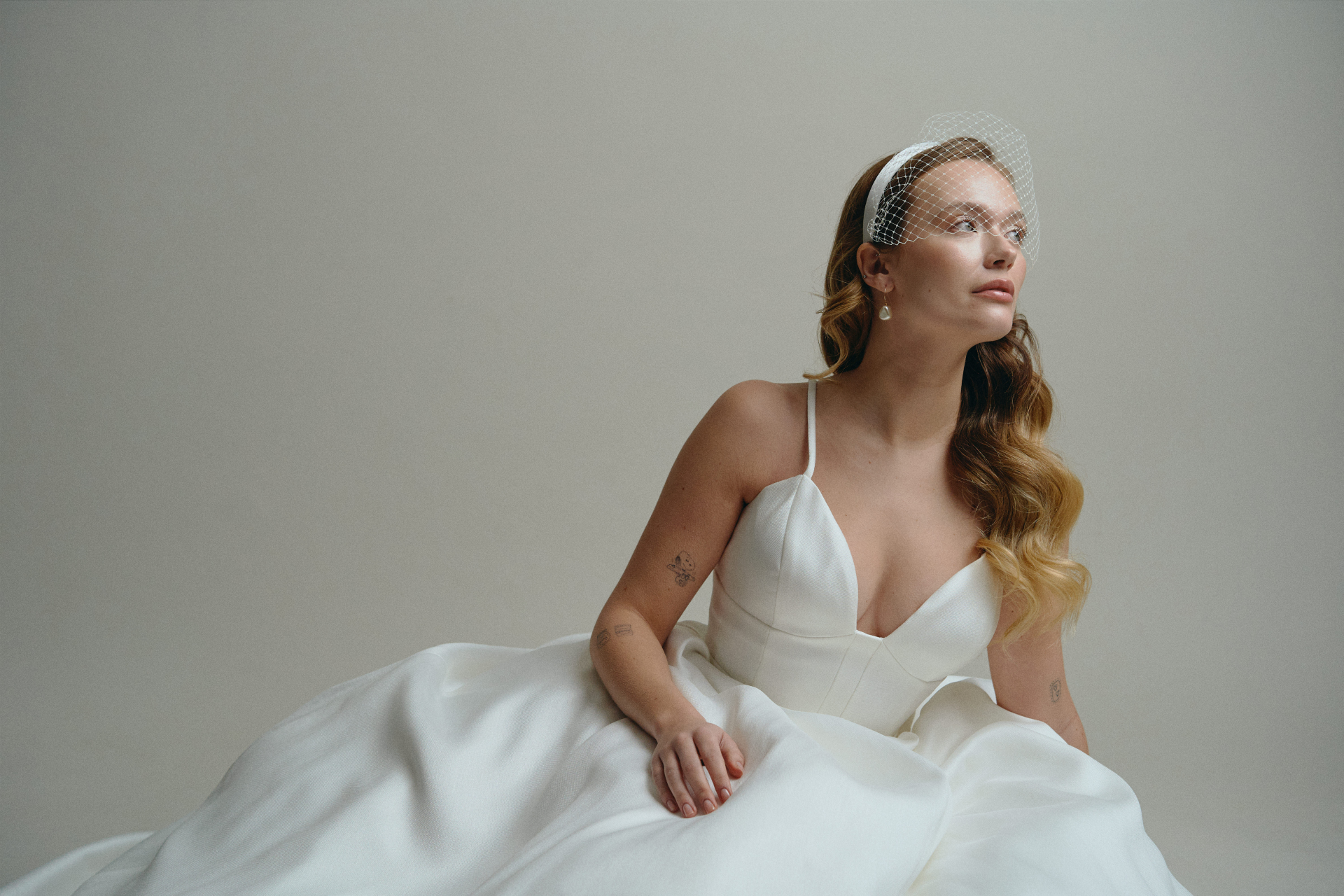 Model wears birdcage veil headband and statement pearl earrings