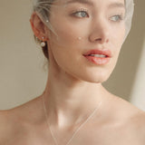 bride wears an ivory tulle mask style micro veil with small pearl embellishment with a baroque coin pearl necklace and crystl and pearl stud drop earring