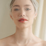 bride wears an ivory tulle mask style micro veil with small pearl embellishment with a baroque coin pearl necklace and crystl and pearl stud drop earring