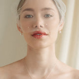 bride wears an ivory tulle mask style micro veil with small pearl embellishment with a baroque coin pearl necklace and crystl and pearl stud drop earring