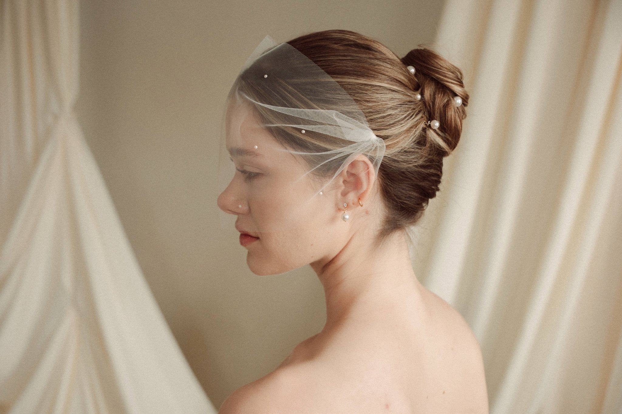 bride wears an ivory tulle mask style micro veil with small pearl embellishment with a baroque coin pearl necklace and crystl and pearl stud drop earring