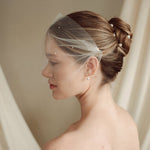 bride wears an ivory tulle mask style micro veil with small pearl embellishment with a baroque coin pearl necklace and crystl and pearl stud drop earring