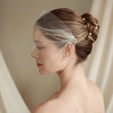 bride wears an ivory tulle mask style micro veil with small pearl embellishment with a baroque coin pearl necklace and crystl and pearl stud drop earring