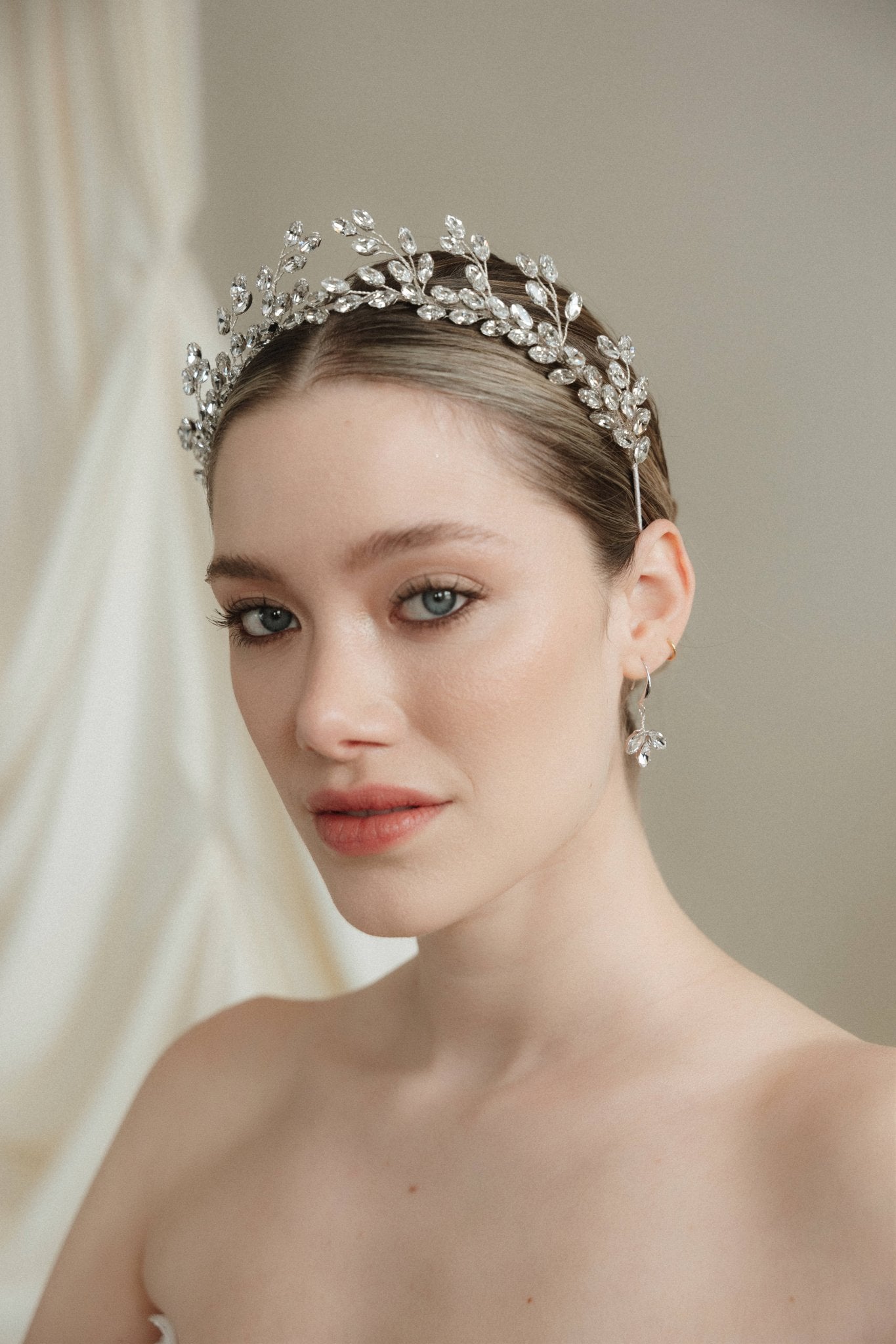 Woman wearing a sparkling tiara against a neutral background