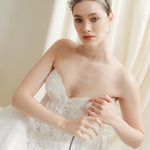 Woman in a white wedding dress with a tiara against an ivory draped  background