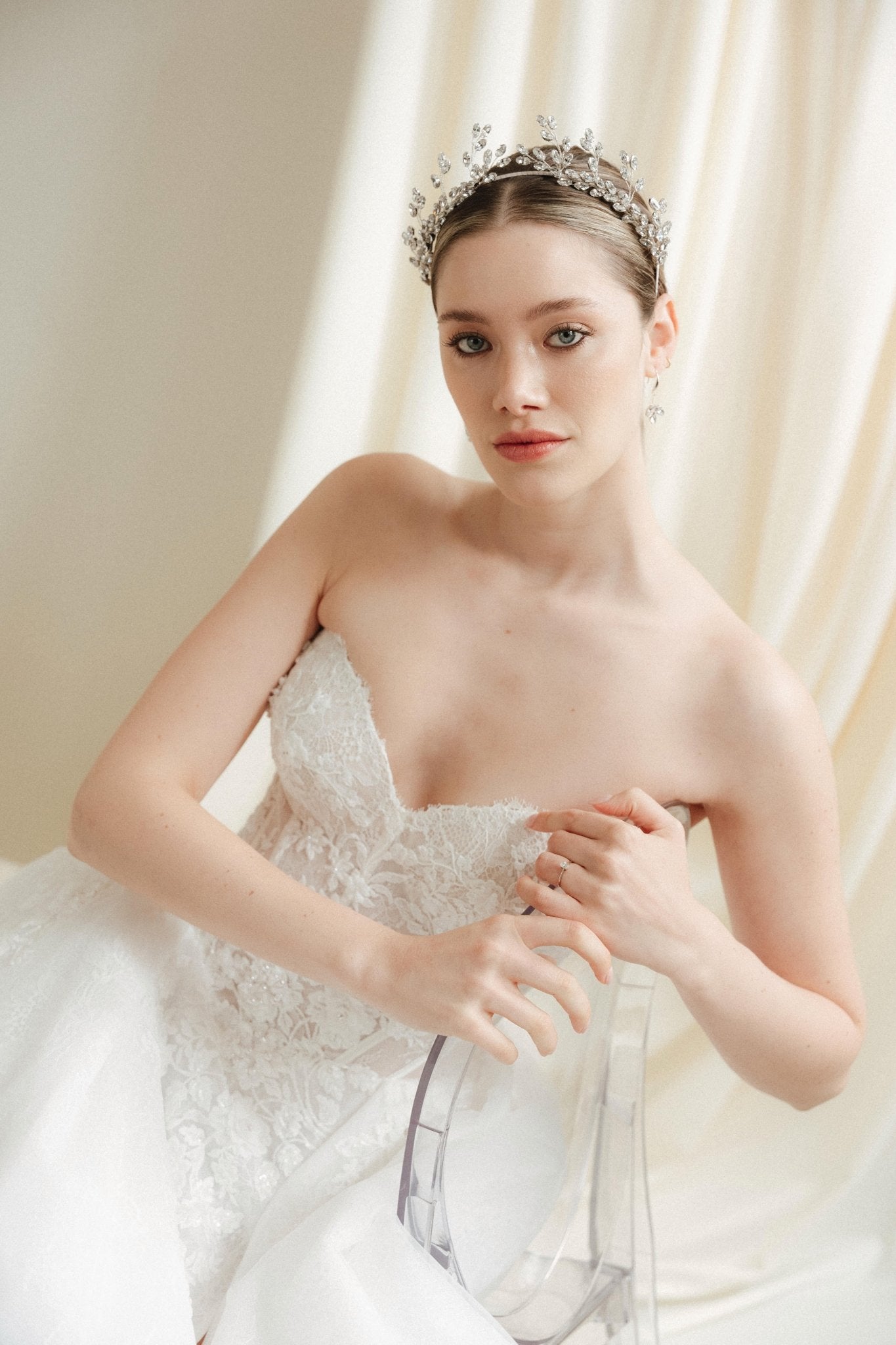 Woman in a white wedding dress with a tiara against an ivory draped  background