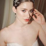 A bride wears a sparling silver crystal crown with hair pins positioned at it's base to create the effect of leaves growing out of the base of the headpiece 