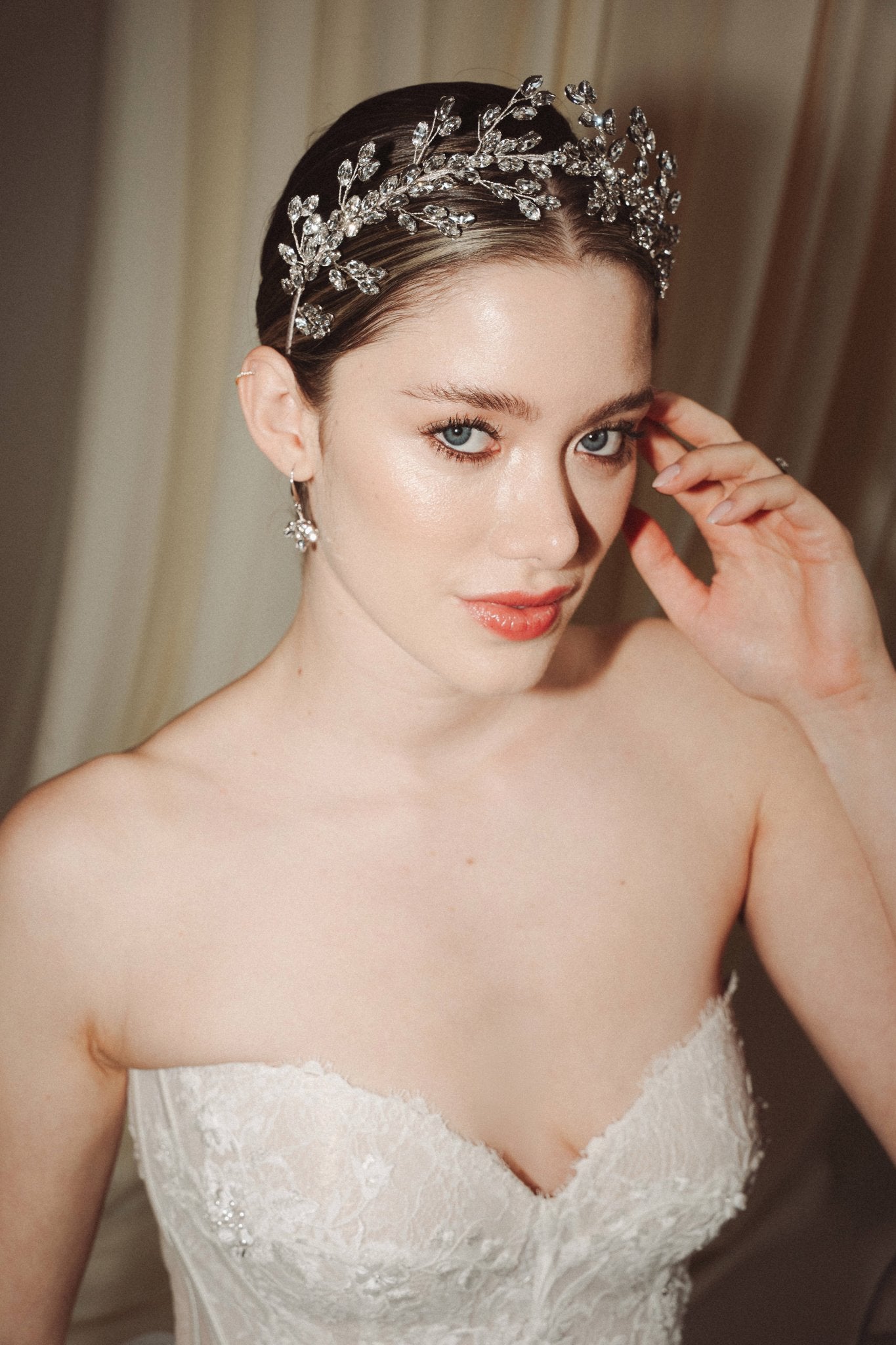 A bride wears a sparling silver crystal crown with hair pins positioned at it's base to create the effect of leaves growing out of the base of the headpiece 