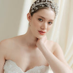 A bride wearing a sparkling silver crystal crown with hair pins positioned at it's base to create the effect of leaves growing out of the base of the headpiece 