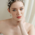 A bride wears a sparling silver crystal crown with hair pins positioned at it's base to create the effect of leaves growing out of the base of the headpiece 