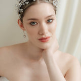A bride wears a sparling silver crystal crown with hair pins positioned at it's base to create the effect of leaves growing out of the base of the headpiece 