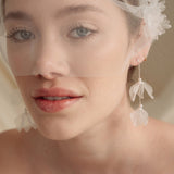 Bride wears an ivory tulle veil with face-framing silk flowers with coordinating silk flower and pearl long drop earrings