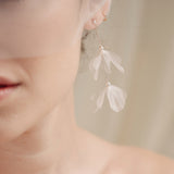 Bride wears an ivory tulle veil with face-framing silk flowers with coordinating silk flower and pearl long drop earrings