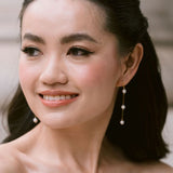 bride wears dainty pearl long drop earrings