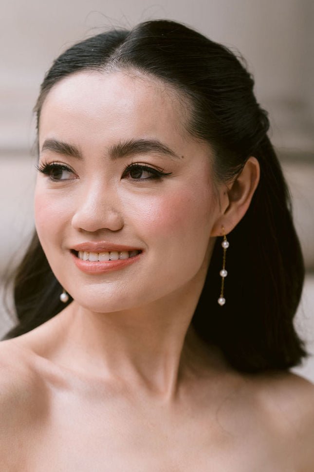 bride wears dainty pearl long drop earrings