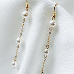 bride wears dainty pearl long drop earrings