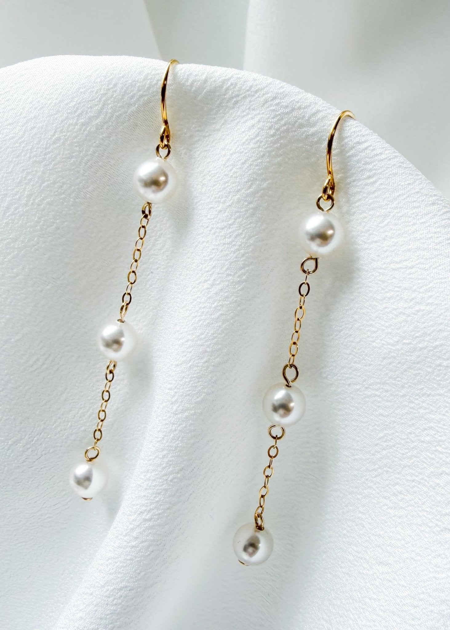 bride wears dainty pearl long drop earrings