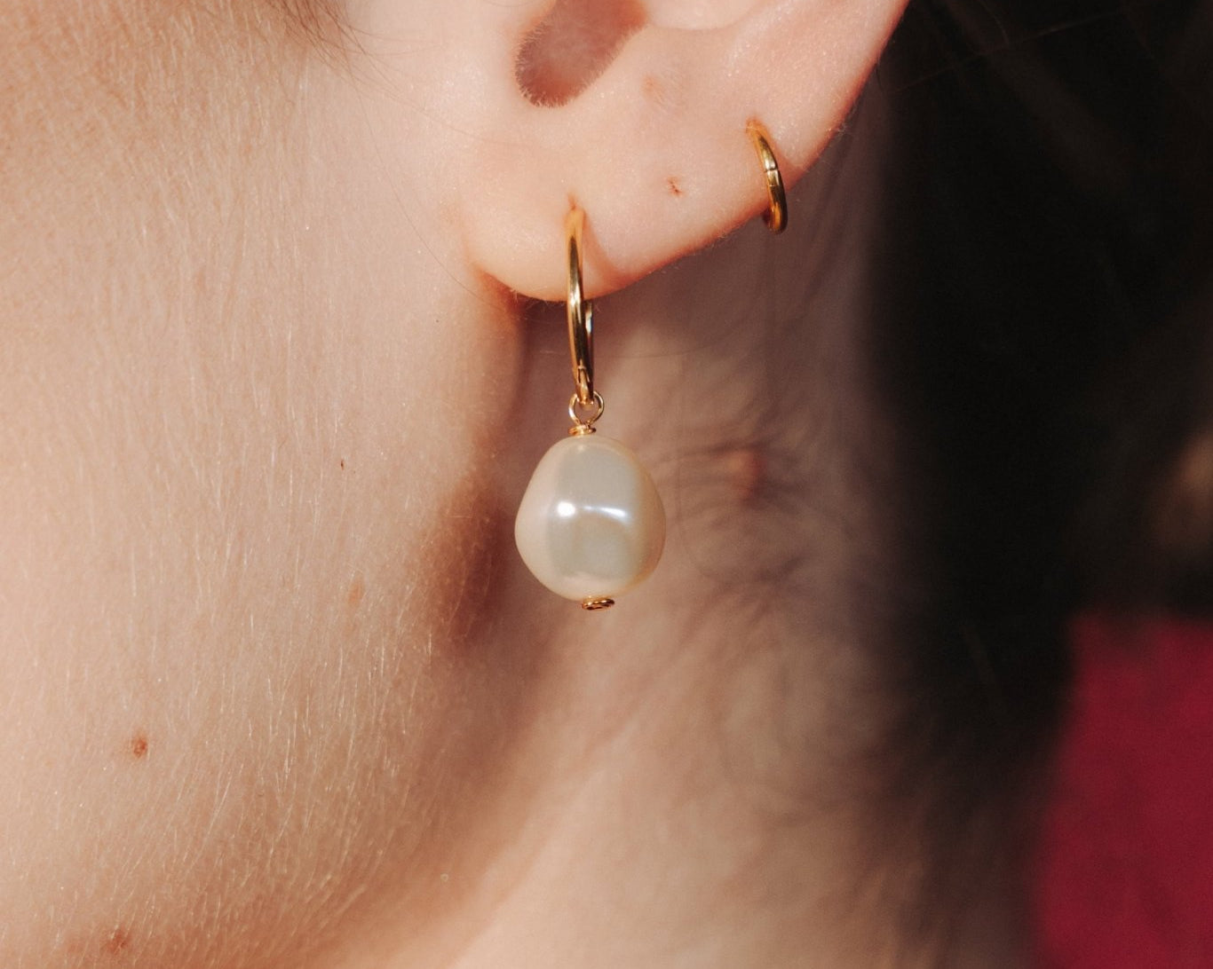 Close-up of an ear wearing a gold hoop earrings with a single vegan baroque pearl