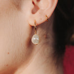 Close-up of an ear wearing a gold hoop earrings with a single vegan baroque pearl